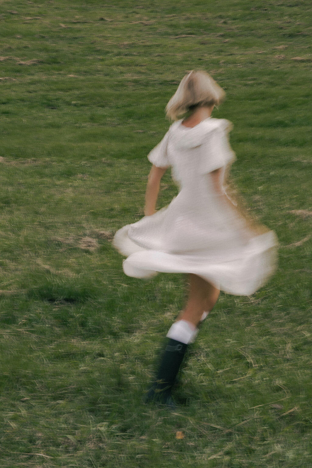 Woman in a white dress running on a grassy field