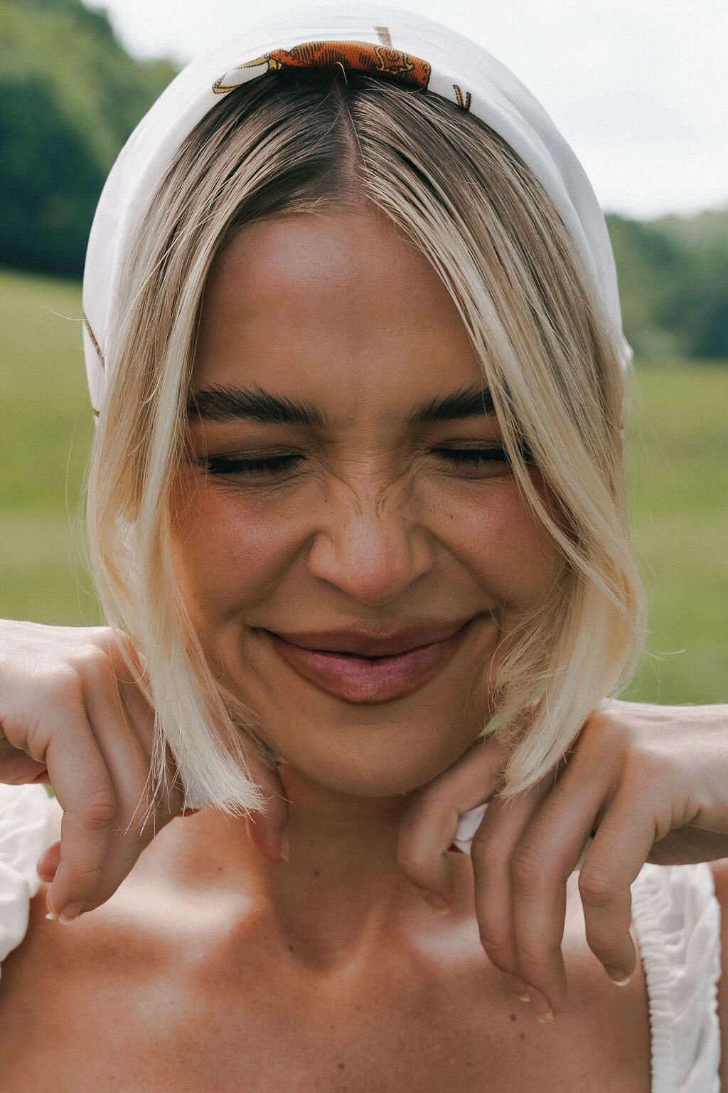 Woman with blonde hair wearing a white headband in a natural setting